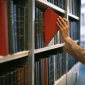 Hand pulling book from bookshelf