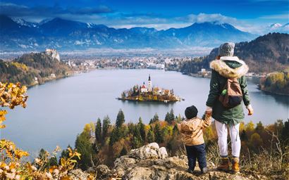 Family travel Europe. Mother with son looking on Bled Lake. Autumn or Winter in Slovenia, Europe. Top view on Island with Catholic Church in Bled Lake with Castle and Mountains in Background.