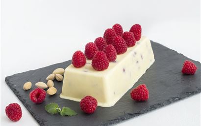 Cheese ice-cream with fresh raspberry and pistachios on black square plate and white background