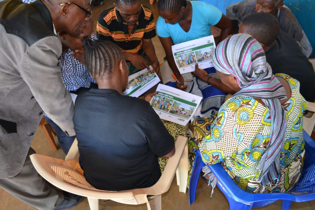 Farmers discussing the effectiveness of banana print material during a pre-test activity in Tanzania