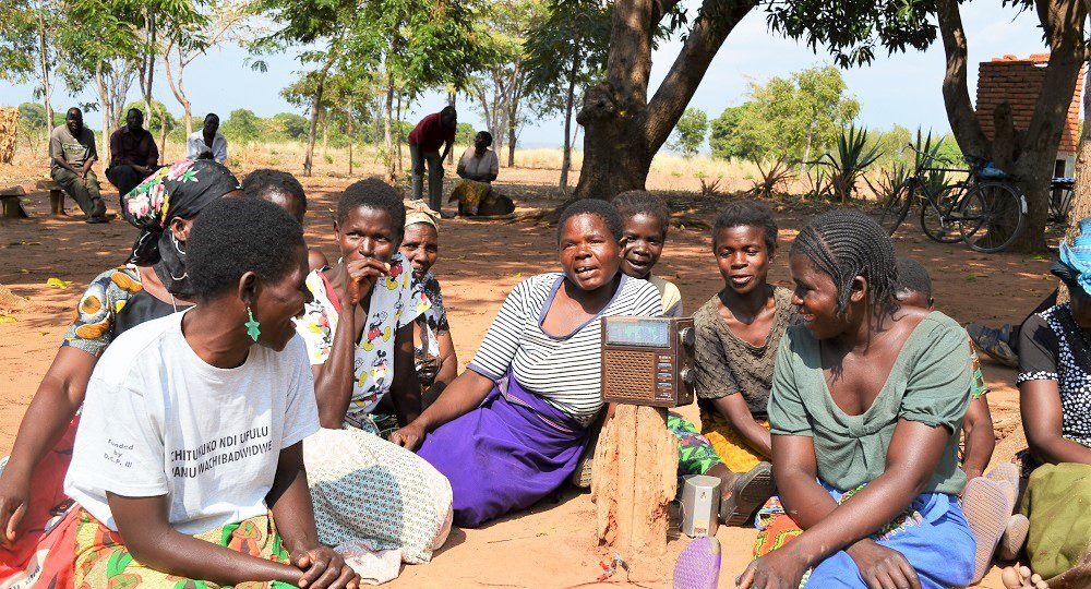 Smallholder farmers gather around a radio in Malawi to hear extension messages on how to grow more profitable crops