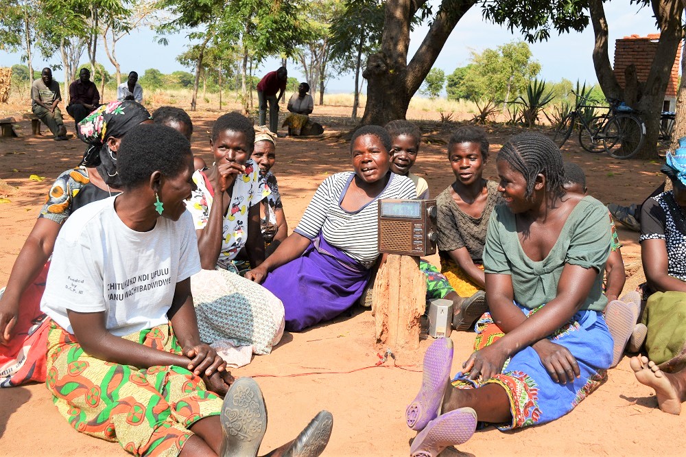 Smallholder farmers gather around a radio in Malawi to hear extension messages on how to grow more profitable crops 
