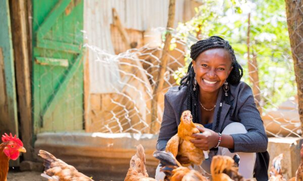 Mary Mueni sits proudly with her flock of chickens