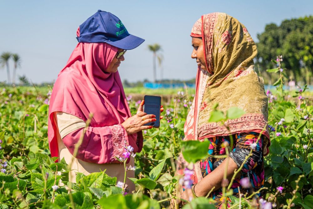 Two farmers in a field using digital technology