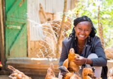 Mary Mueni sits proudly with her flock of chickens
