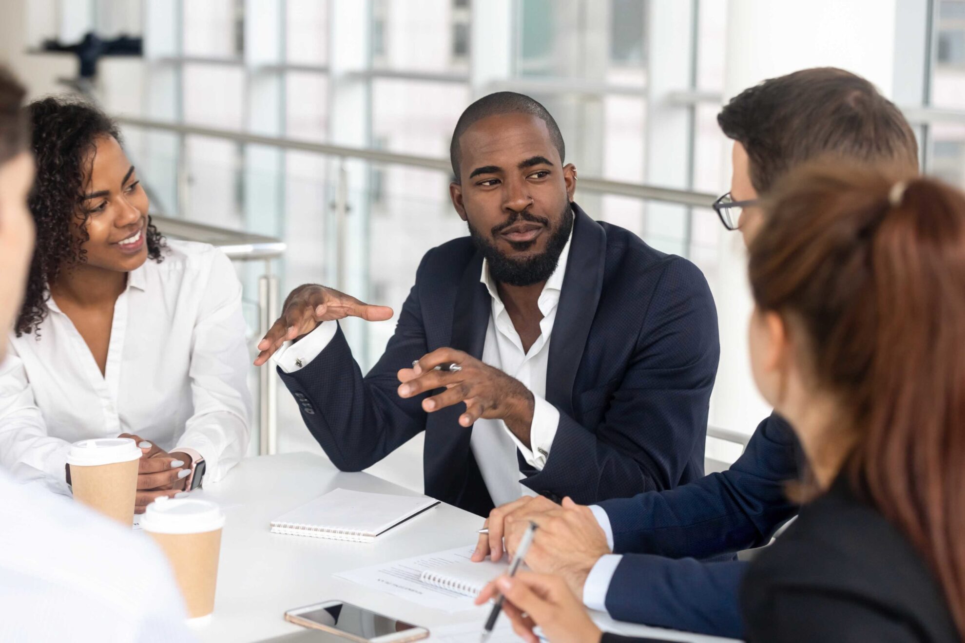 Black millennial boss leading corporate team during briefing in boardroom Millennial employees gathered in boardroom for training, black boss ceo leader leading corporate team during seminar learning at modern office. Internship and leadership coaching and education concept