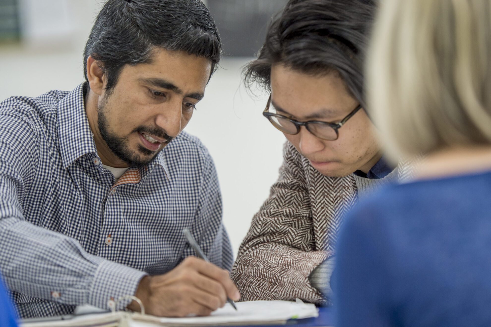 University Tutor A multi-ethnic group of adults are studying together after class. They are in a university classroom taking continuing adult education classes.